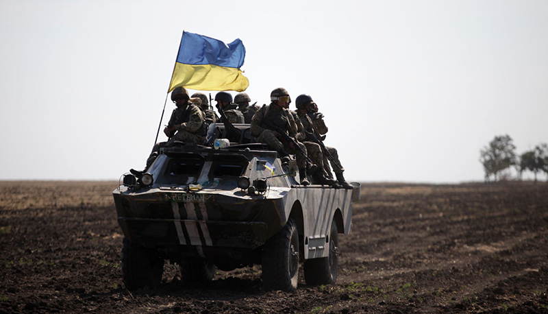 Soldiers ride on a vehicle flying the Ukrainian flag