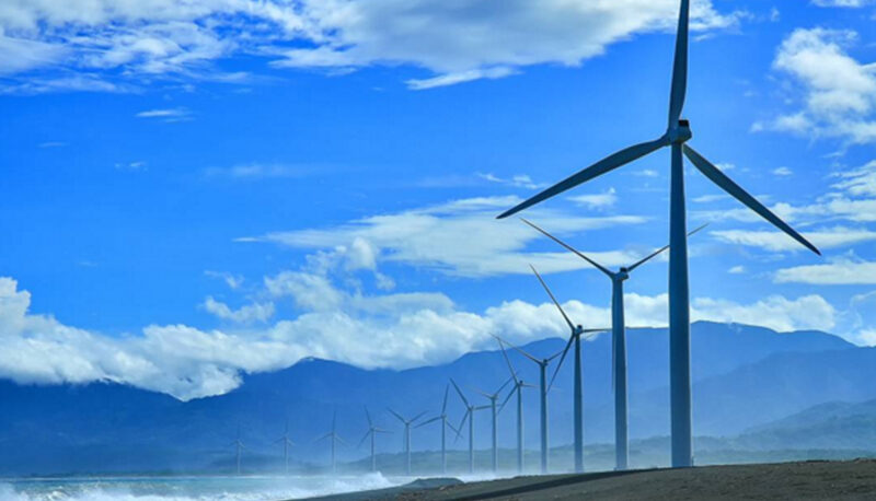 Windmills against a blue sky with scattered clouds.