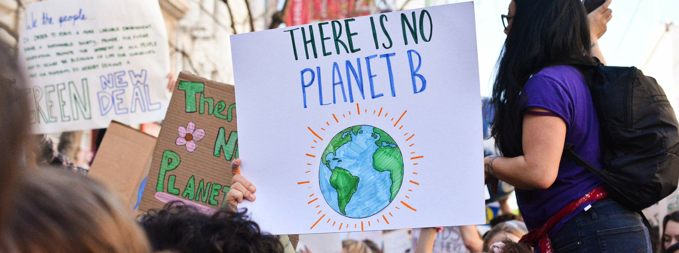 A group of young people at a climate protest, one of them with a sign that reads 