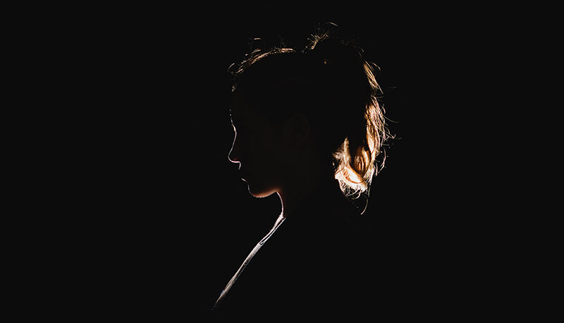 A woman's silhouette against a dark background.