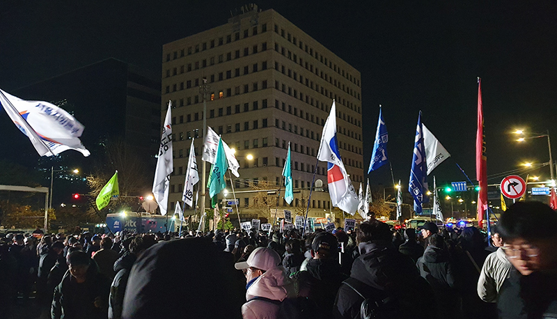 Protestors waving flags as they demonstrate against martial law in South Korea, 2024.